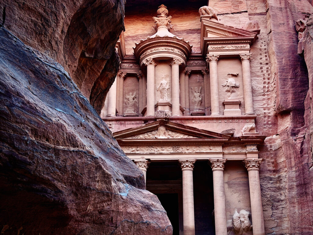 الخزنة في البتراء، الأردن، تقع بين منحدرات صخرية ضخمة من الحجر الرملي على طريق السيق. تُعدّ الخزنة تحفة معمارية نبطية قديمة في البتراء، الأردن، وهي موقع تراث عالمي لليونسكو ووجهة سياحية شهيرة. البتراء، وادي موسى، الأردن، الشرق الأوسط.